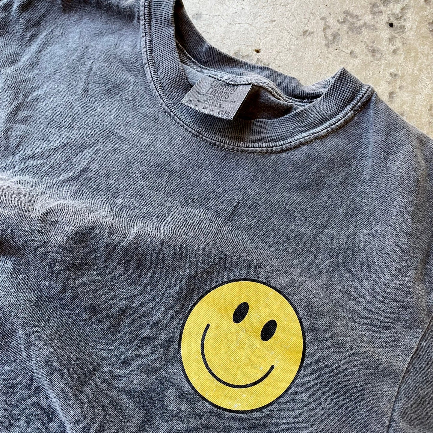 Close up of smiley face on comfort colors pepper t-shirt