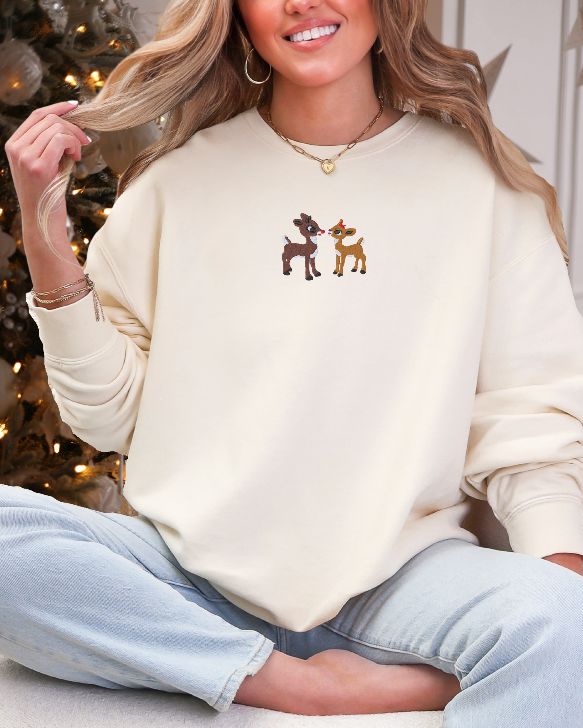 Cream crewneck with Rudolph the Red-Nosed Reindeer and Clarice embroidered on it.