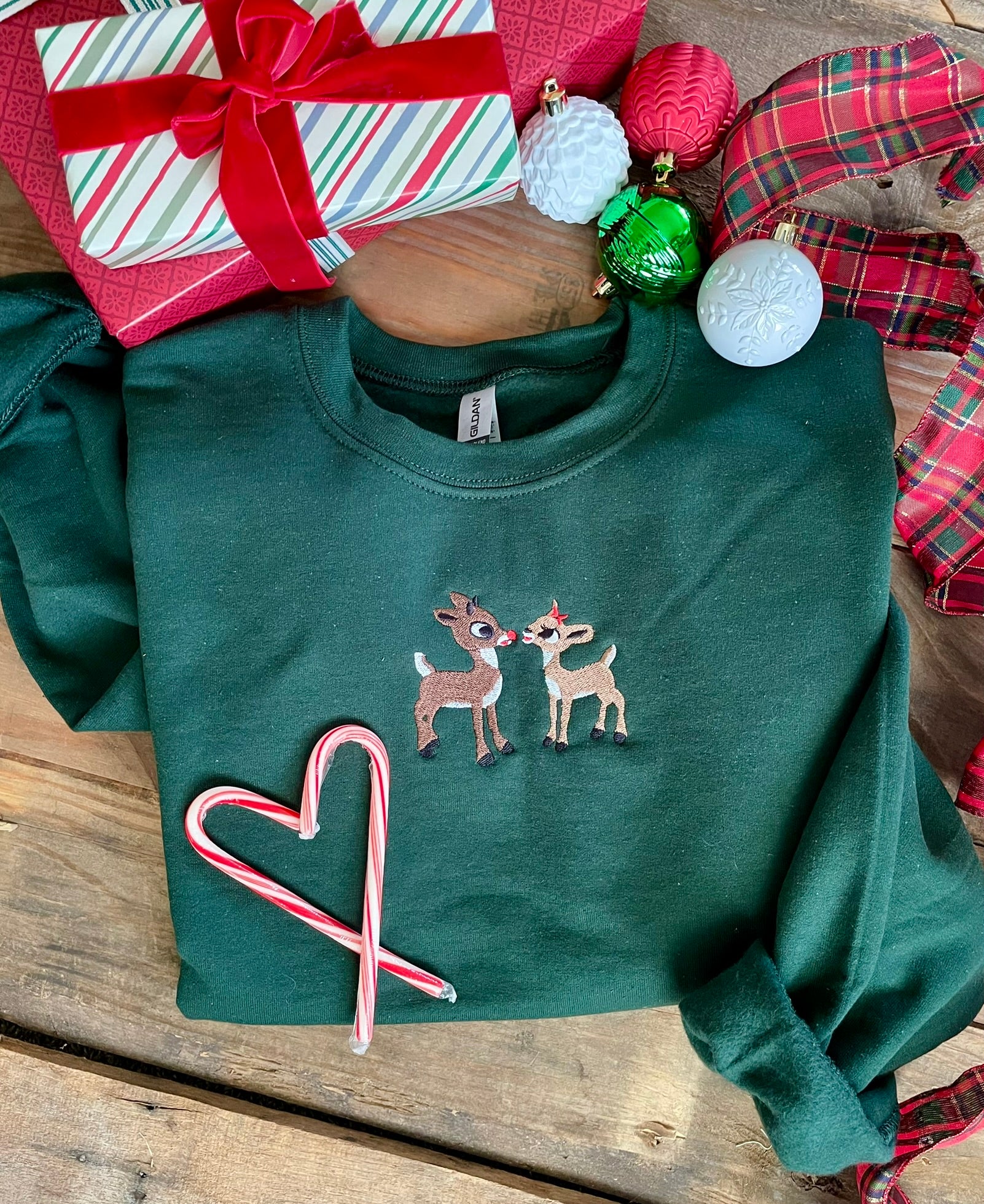 Green Crewneck sweatshirt with Rudolph and Clarice embroidered on it.
