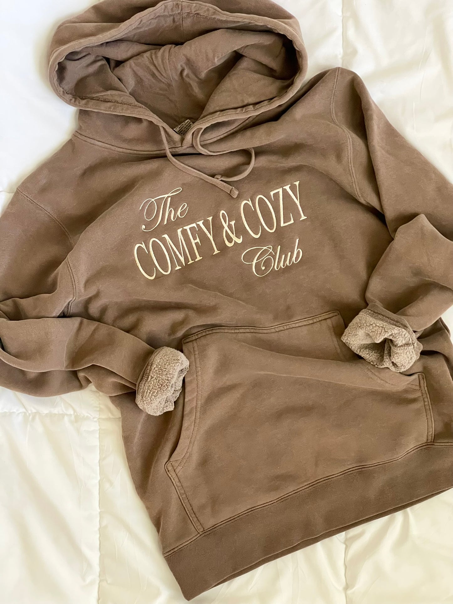 Brown hoodie with 'The Comfy & Cozy Club' text on a light background