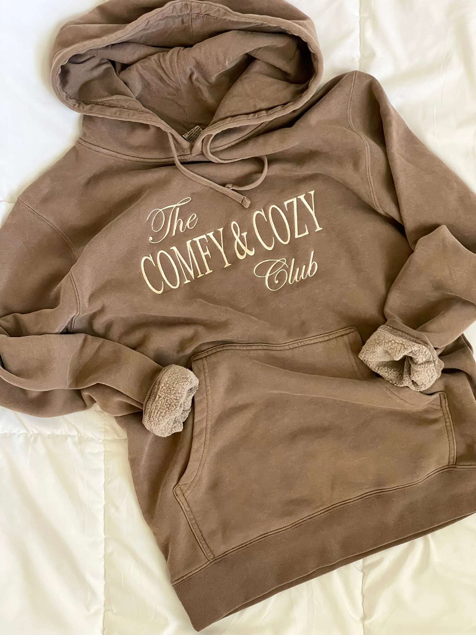 Brown hoodie with 'The Comfy & Cozy Club' text on a light background