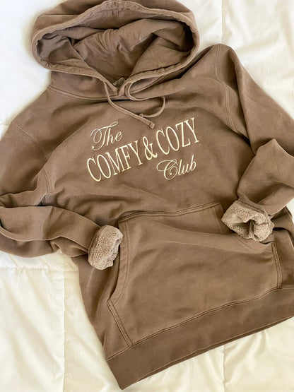 Brown hoodie with 'The Comfy & Cozy Club' text on a light background