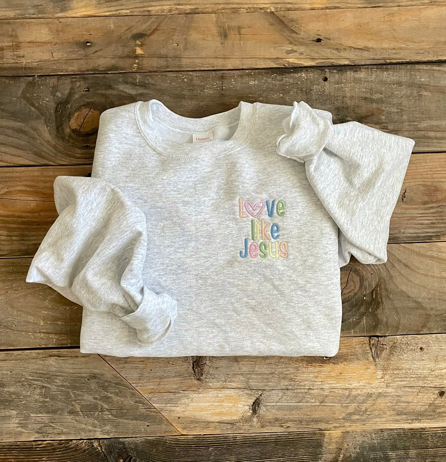 Ash gray crewneck sweatshirt with LOVE LIKE JESUS embroidered in pastels