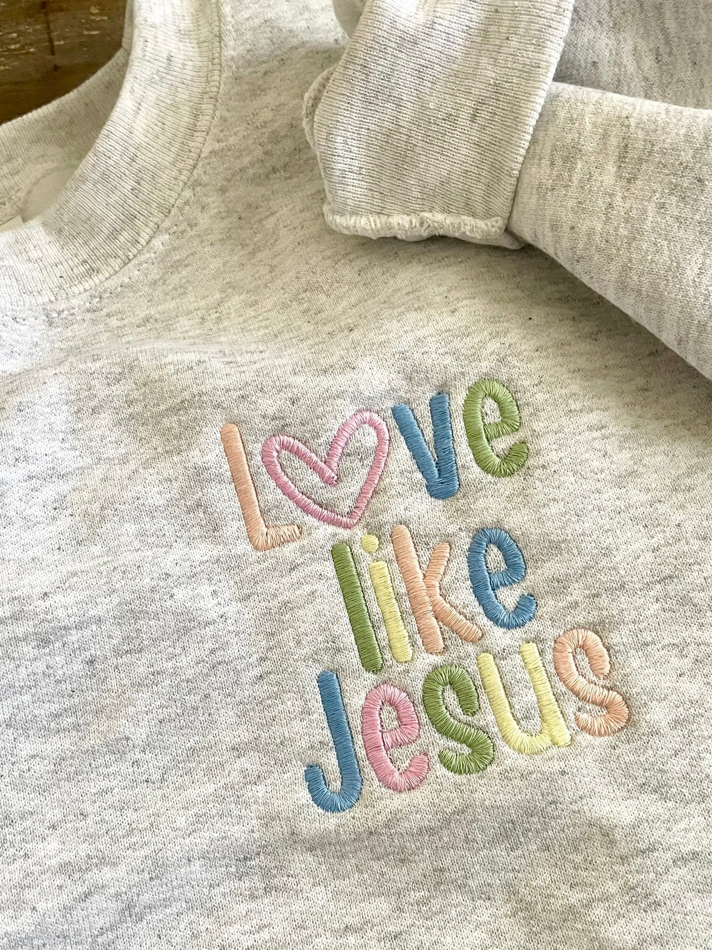 Ash gray crewneck sweatshirt with LOVE LIKE JESUS embroidered in pastels