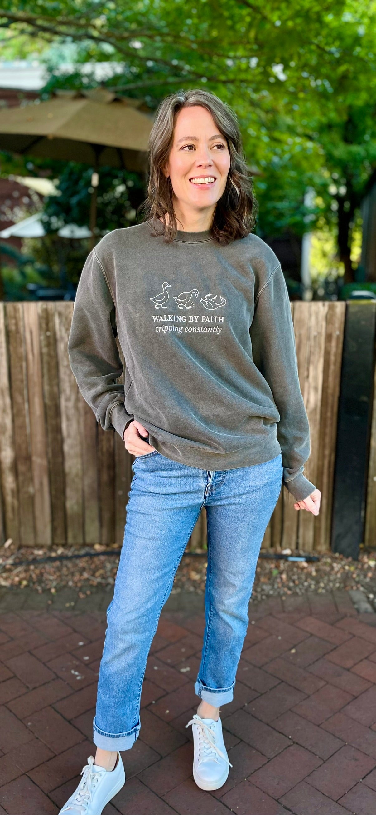 faded black crewneck embroidered with 3 geese and phrase "Walking by Faith tripping constantly"