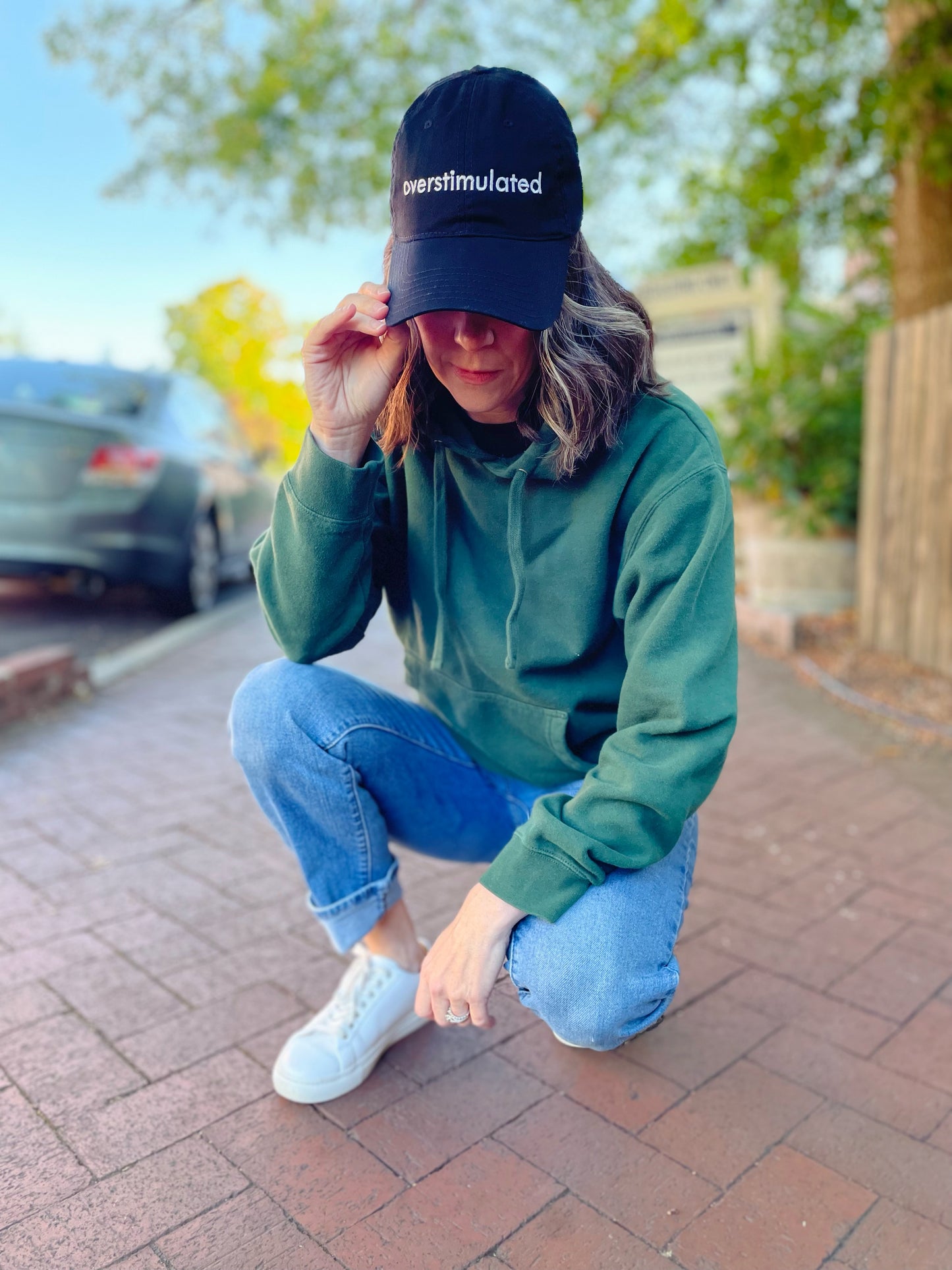 overstimulated embroidered in white on a black dad hat