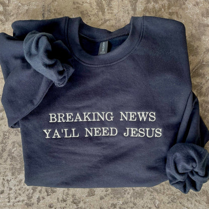 Black crewneck sweatshirt with Y'all Need Jesus Embroidered on it in white