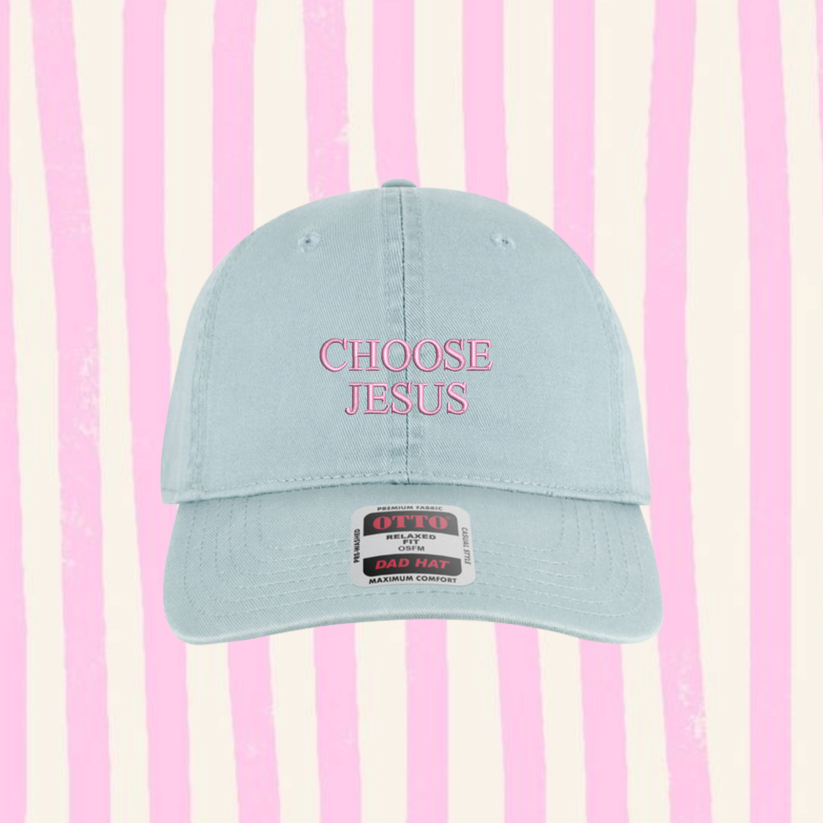 A light blue baseball cap with 'CHOOSE JESUS' embroidered in pink on the front, set against a pink and cream vertical striped background.
